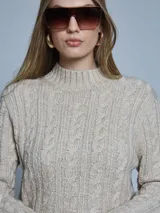 Sweater de punto con diseño de ochos, cuello alto y manga larga. Presenta una textura trenzada gruesa y un calce holgado.