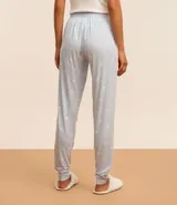 Pantalón de pijama celeste con estampado de patitas blancas, cintura elástica y puños ajustados.