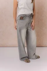 Jean wide leg de tiro alto color gris con efecto lavado desgastado, corte holgado, diseño de cinco bolsillos y cierre frontal con botón y cremallera.