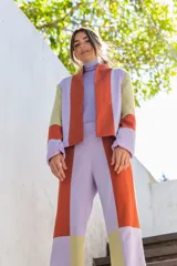 Chaqueta de corte recto con diseño multicolor en bloques de color naranja, lila y amarillo. Presenta cuello mao, mangas largas con puños vueltos y bolsillos laterales.