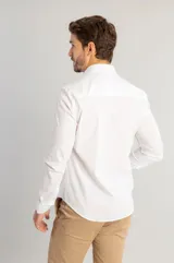 Camisa de vestir blanca de manga larga, con cuello clásico y cierre frontal de botones. Confeccionada en tejido de tricolina con elastano para mayor comodidad y ajuste.