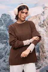 Buzo oversize de tejido de punto acanalado en color marrón, con cuello redondo y mangas largas. Presenta un diseño holgado con aberturas laterales en el ruedo.