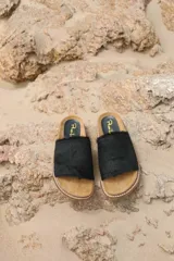 Sandalias de cuero negro con tira ancha de pelo y suela plana de corcho.