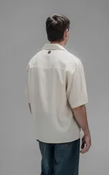 Camisa de manga corta con cuello cubano y cierre frontal de botones, de corte oversize y diseño minimalista.