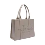 Bolso tipo tote de Marc Jacobs, confeccionado en cuero granulado de alta calidad. Presenta un diseño estructurado con doble asa superior y el nombre del modelo estampado en el frente.