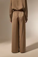 Pantalon de vestir de corte ancho y tiro alto, confeccionado en tela de viscosa con acabado satinado. Presenta cintura elástica y diseño fluido.