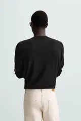 Jersey color crudo de tejido de punto, con cuello redondo y mangas largas. Corte amplio y terminaciones en rib.