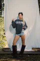 Crewneck de manga larga color gris oscuro con efecto lavado, estampado frontal con el texto "ENDLESS SUMMER" y estrellas estampadas a lo largo de las mangas.