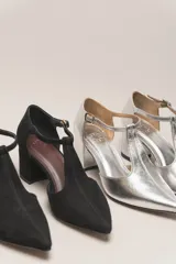 Sandalia de cuero color bordó, con acabado charolado, punta fina y tacón cuadrado de 5 cm. Presenta una tira en forma de T sobre el empeine y una correa con hebilla alrededor del tobillo.