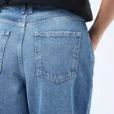 Jean de corte regular y cintura alta, confeccionado en denim azul con lavado stonewash. Presenta un diseño de pierna recta con un dobladillo ancho en la parte inferior.