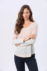 Remera de manga larga con cuello redondo y cierre frontal parcial con botones. Presenta un diseño de rayas horizontales en tonos pastel sobre una base beige, con aberturas laterales en el ruedo.
