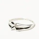 Brazalete rígido plateado con forma de flor y detalle de strass.