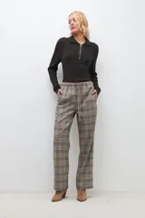 Pantalón largo de corte recto con estampado de cuadros escoceses en tonos beige, marrón y negro. Tiene cintura elástica con cordón ajustable.
