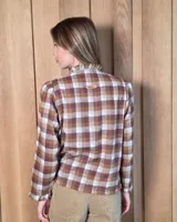 Camisa de algodón con estampado de rayas verticales finas, cuello alto con volados, cierre frontal con botones dobles y mangas largas con puños elásticos terminados en volados.