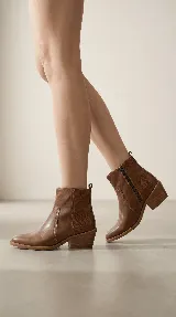 Bota corta tipo chelsea de cuero negro, con panel lateral texturizado y taco cuadrado bajo.