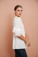 Camisa blanca de manga larga con escote redondo, puntillas y tablas al frente.