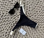Bombacha de bikini colaless, color crudo texturizado en la parte trasera y negro brillante en la parte delantera. Tiene tiras regulables en los laterales.