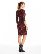 Vestido corto de seda fría con estampado floral en tonos rojo y negro. Presenta cuello volcado, mangas tres cuartos y un detalle de drapeado lateral en la cintura.