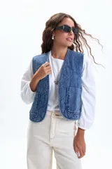 Chaleco sin mangas de jean azul, con diseño acolchado capitoné y cuello en V. Posee dos bolsillos frontales de parche.