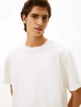 Remera de punto de algodón moteado, color blanco, con cuello redondo y escudo con monograma TH bordado en tono sobre tono en el pecho. Presenta un corte amplio y cómodo.