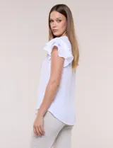 Blusa de gasa color azul, con cuello en V y abotonadura parcial. Cuenta con mangas cortas tipo mariposa con doble capa de volados y silueta fluida.