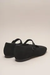 Zapato plano estilo Mary Jane de cuero negro, con punta fina y tira ajustable con hebilla sobre el empeine.