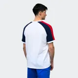 Remera de algodón azul con mangas raglán rojas y detalles en blanco en cuello y puños. Incluye logo de Umbro bordado en el pecho y escudo del Club Nacional de Football.