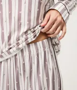 Pijama largo de 2 piezas, compuesto por una blusa de manga larga con escote en V y un pantalón de corte recto, confeccionados en tejido efecto piel de durazno con estampa de rayas y ribetes contrastantes en cuello, puños y ruedo.