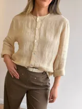 Camisa de lino color beige, con diseño ligeramente oversize, cuello mao y cierre frontal con botones.