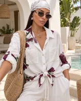 Camisa blanca de manga larga con estampado floral en tonos bordó y verde, cuello camisero, cierre frontal de botones y bolsillos en el pecho con apliques de lentejuelas.