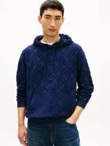 Buzo con capucha de Tommy Hilfiger, color azul marino, con patrón jacquard geométrico en relieve, bolsillo frontal tipo canguro y cordones ajustables en el cuello. Cuenta con puños y dobladillo acanalados, y detalle de la bandera bordada en el puño.