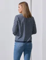 Blusa de gasa estampada con líneas verticales negras sobre fondo beige, de manga larga con puño abotonado. Espalda con abertura y botón.