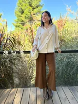 Camisa de corte clásico con estampado de rayas verticales en tonos beige y blanco, cuello camisero, cierre frontal de botones y mangas largas con puños vueltos.