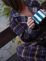 Conjunto de pijama a cuadros con ribetes en color lila, compuesto por camisa de manga larga con botones y pantalón largo.