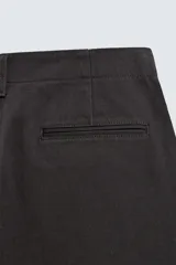 Pantalón chino regular fit de color negro, confeccionado en tejido de algodón. Cuenta con bolsillos frontales, detalle de bolsillo cerillero, bolsillos traseros de doble vivo y cierre frontal con cremallera y botón.