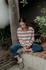 Remera de manga larga con cuello polo y cierre frontal de botones. Presenta un diseño a rayas horizontales en tonos bordó, blanco y celeste.