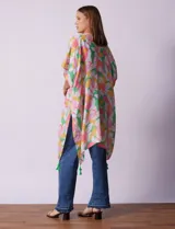 Kimono tejido con estampado floral multicolor y terminación de ruedo con borlas verdes.