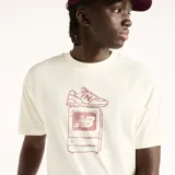 Remera New Balance de hombre, color blanco off-white, con corte amplio y estampa frontal de estilo pixelado en tono bordó con la silueta de un champión sobre una pantalla.