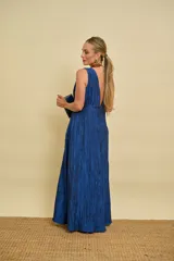 Vestido largo azul con textura arrugada, escote en V pronunciado, sin mangas y falda evasé.