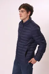 Chaqueta acolchada tipo puffer, color azul marino, con cuello alto y cierre frontal de cremallera.