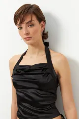 Top negro de satén con cuello halter y espalda descubierta.