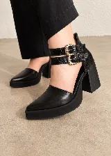 Zapatos de tacón alto en color negro, confeccionados con una combinación de napa, charol y textura efecto croco. Presentan punta fina, plataforma delantera, taco ancho y doble tira con hebillas metálicas en tono oro viejo en el tobillo.