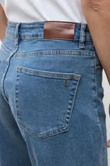 Jean barrel azul de tiro medio, con diseño de perneras curvadas y costuras decorativas a la altura de las rodillas.