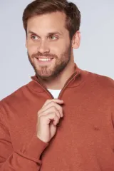 Buzo de tejido fino en hilo de algodón, color rosado, con cuello alto y cierre frontal parcial con detalle en cuero. Presenta puños y ruedo acanalados y un pequeño logo bordado en el pecho.