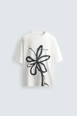 Camiseta de corte relajado confeccionada en algodón, con cuello redondo y manga corta. Presenta un estampado artístico de una flor a trazo grueso en color negro sobre fondo blanco.