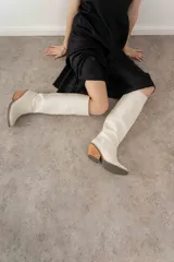 Bota de caña alta color negro, confeccionada en cuero vacuno. Tiene punta fina, taco de 6.5cm y suela de caucho antideslizante.