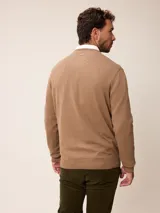 Sweater de punto con cuello en V, manga larga y puños acanalados. Presenta un pequeño logo bordado en el pecho.