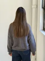 Saco tipo cardigan de punto color gris, con escote en V, cierre frontal de botones y puños y ruedo acanalados.