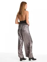 Pantalón wide leg de tela laminada metalizada color blanco, con pretina elástica y lazo de ajuste en la cintura. Cuenta con bolsillos laterales.