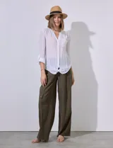Camisa blanca de gasa con cuello a la base y escote en V, abertura central con botones, bolsillo aplicado en el pecho, mangas largas regulables con presilla y terminación anudada opcional.